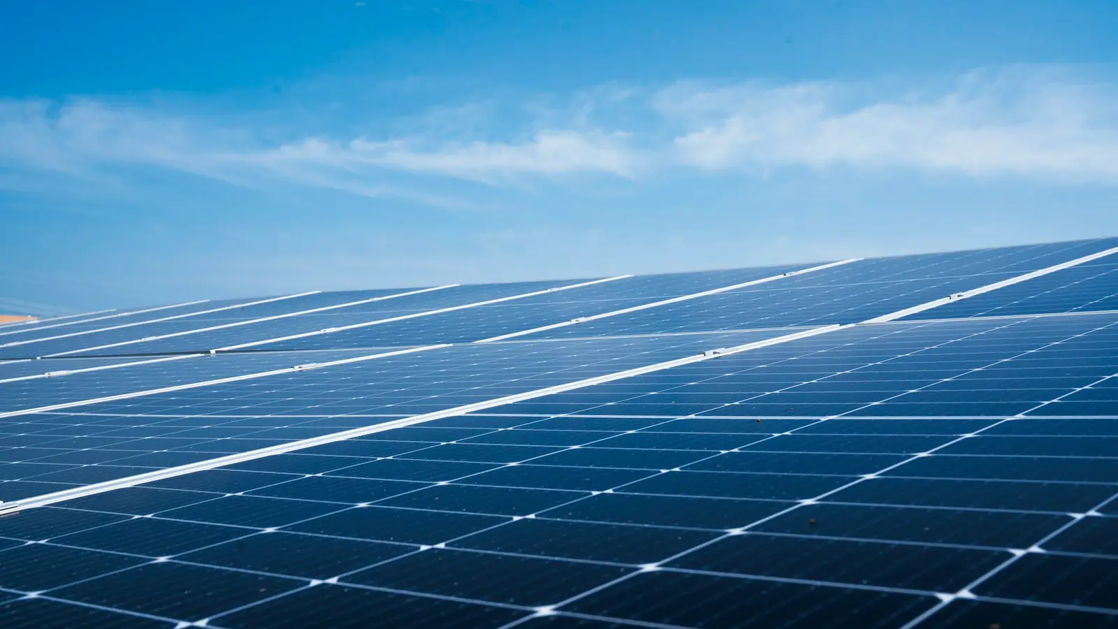 Rijen zonnepanelen onder een blauwe lucht
